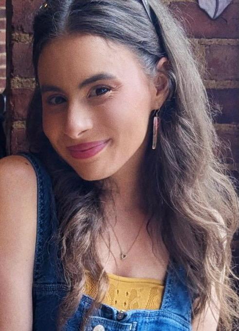 Alyssa smiling wearing overalls and a yellow top