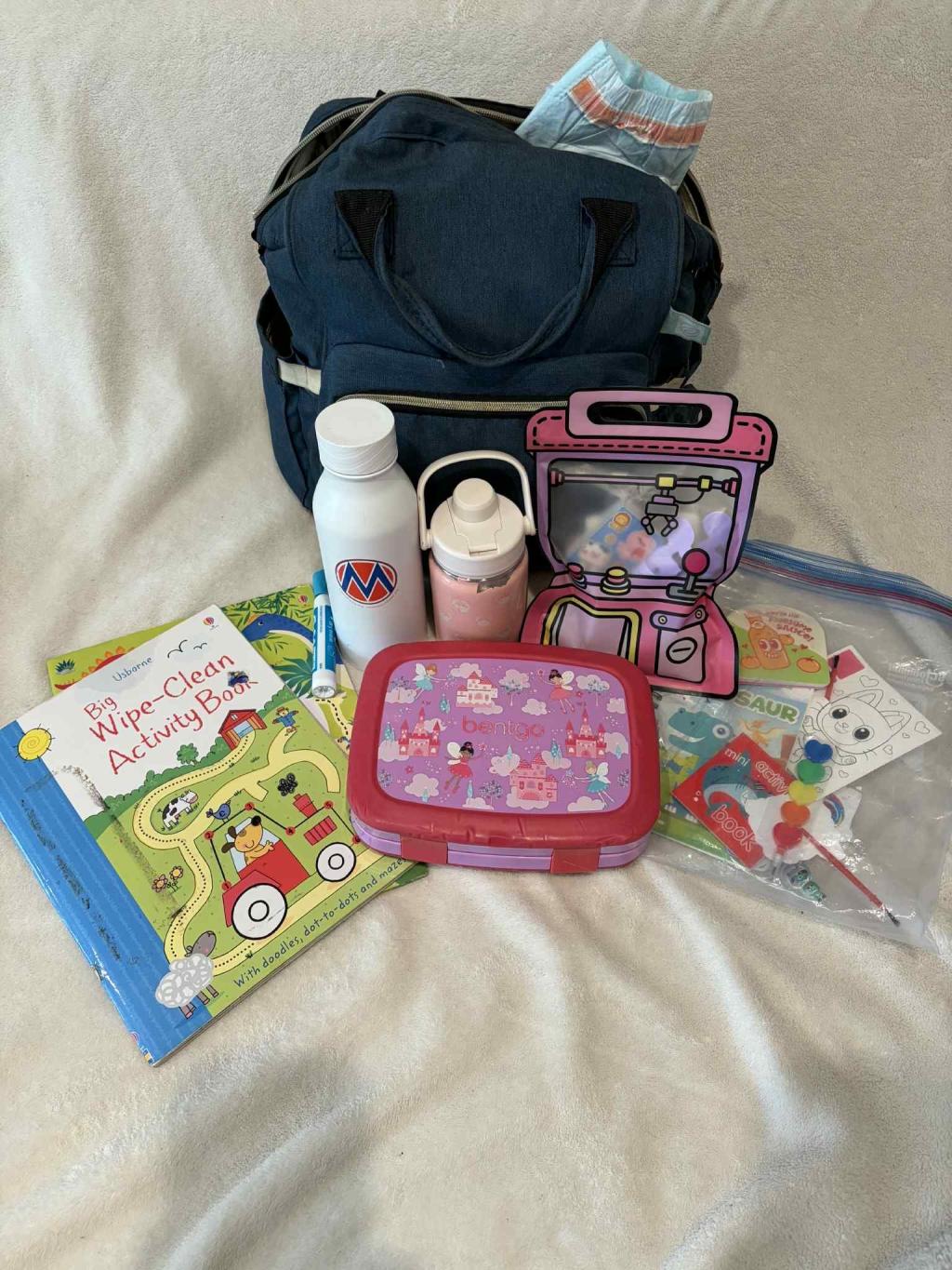 Children's books, bottles, and prep bag with MomsRising sticker logo to take to a MomsRising event