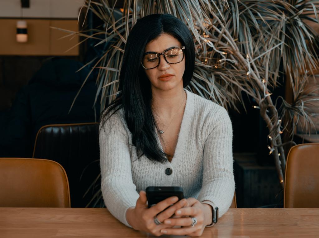 Woman sitting at table reading her mobile phone