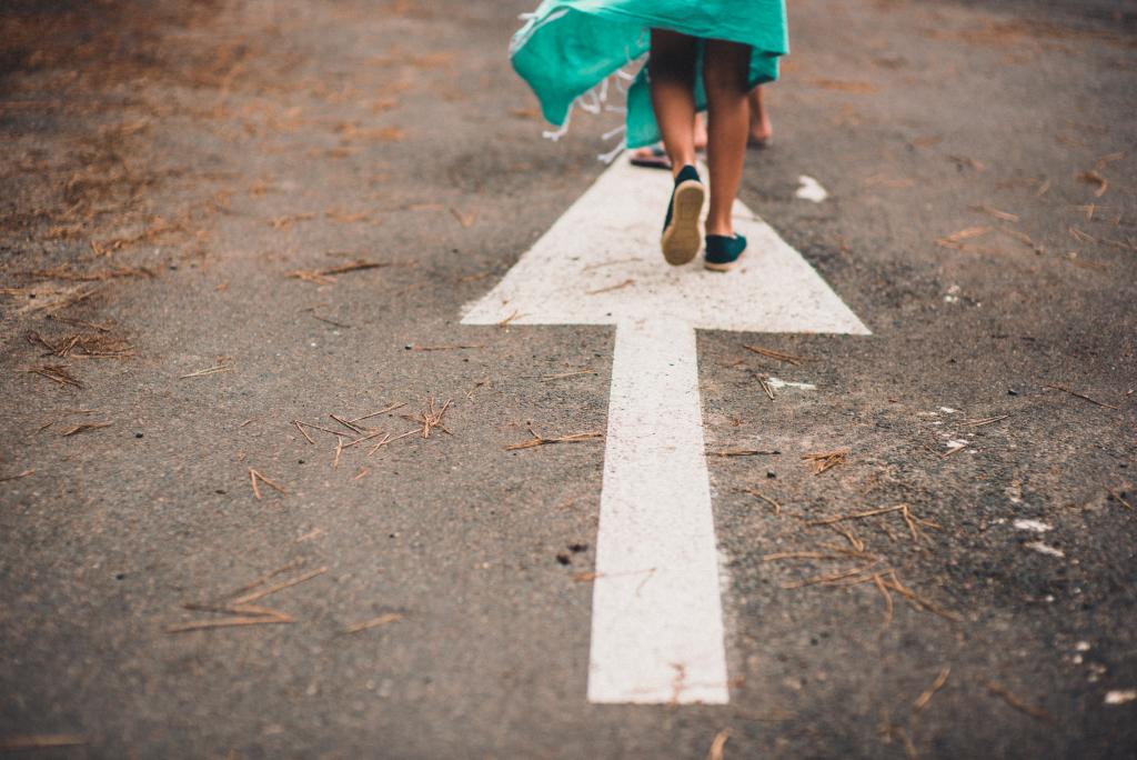 Photo to illustrate The Road Ahead, two people walking on a white painted arrow on a street