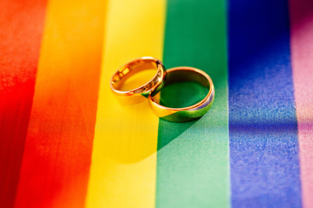 Two wedding bands sitting on top of a gay pride flag