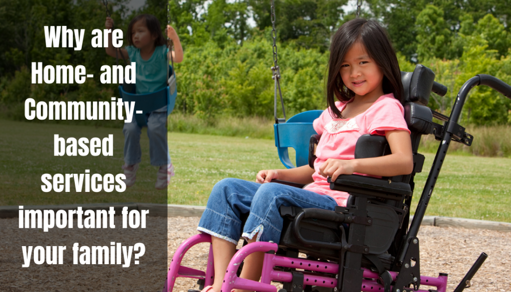 A girl with brown hair in a wheelchair sits smiling on a playground while her sibling swings