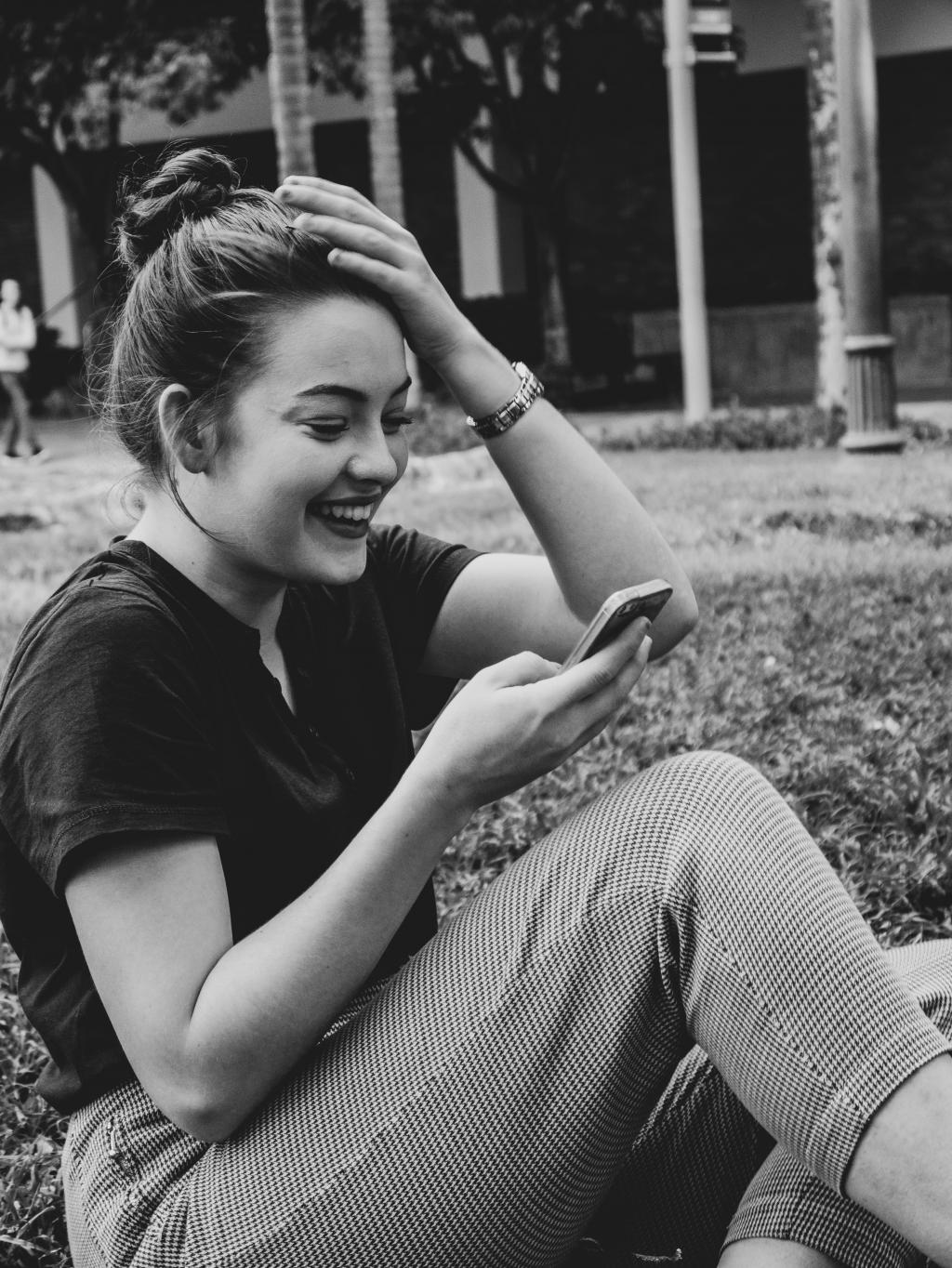 photo of a woman reading her mobile phone and laughing
