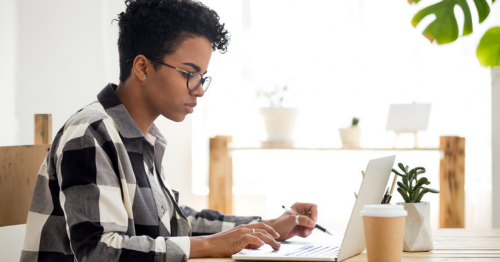 [IMAGE DESCRIPTION: A photo of a person with short curly black hair in profile, facing a laptop.]