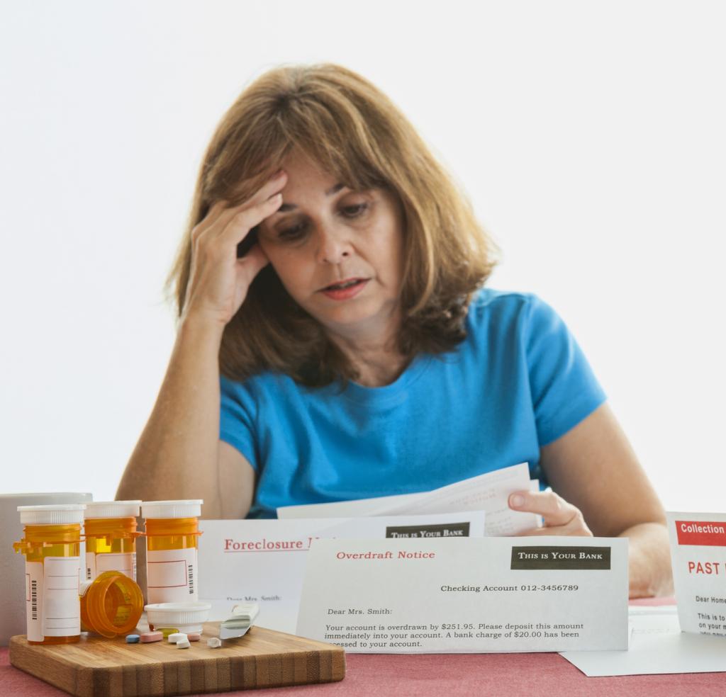 Woman looking at bills with prescription drugs sitting on a table